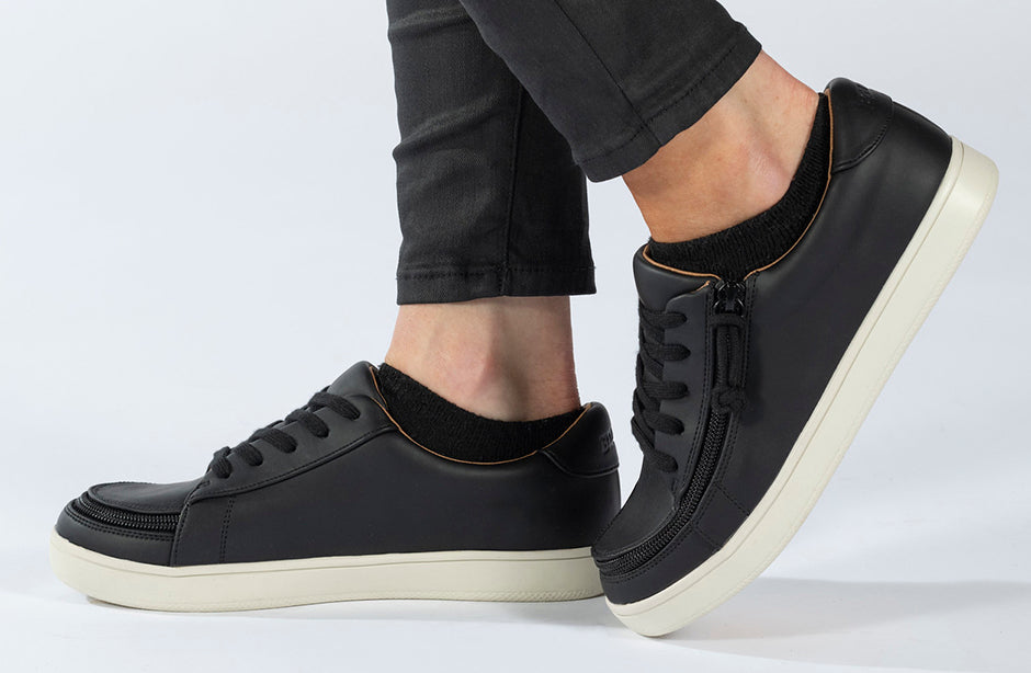 Women's Black BILLY Sneaker Low Tops featuring faux leather and functional laces, shown on a person's feet, emphasizing comfort and elegance.