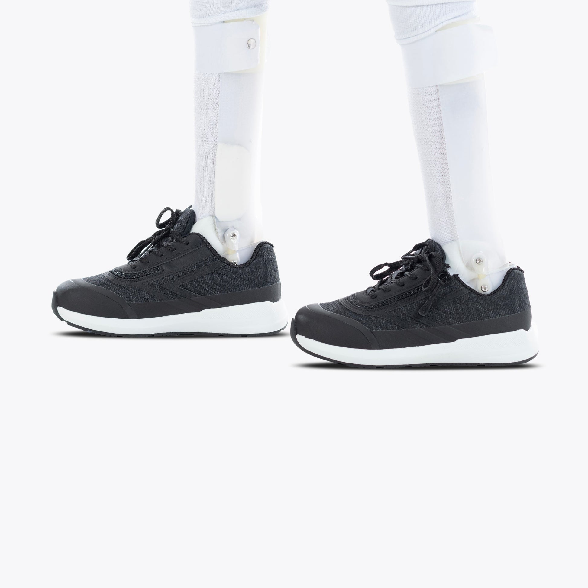 Black BILLY Goat shoes with white socks, featuring a prosthetic leg. AFO-friendly design with a short wrap zipper for easy wearing.